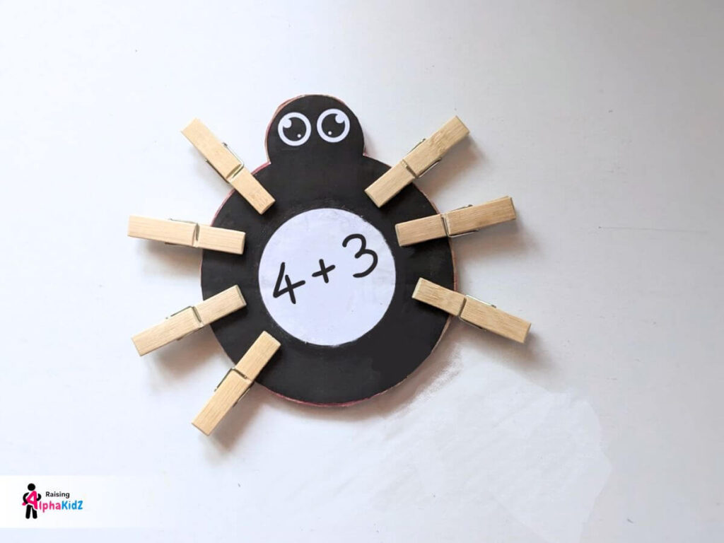 Solving 4 + 3 using clothespin legs on counting spider legs activity
