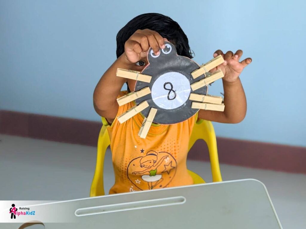 Child clipping clothespin legs to a cardboard spider for counting activity