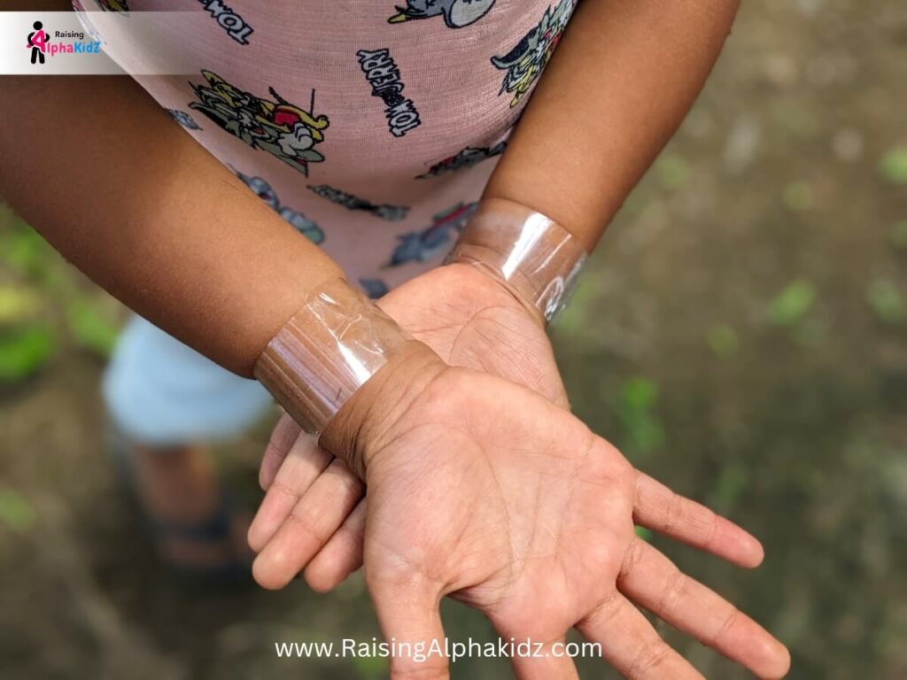 Child hands with sticky tape to make nature bracelet