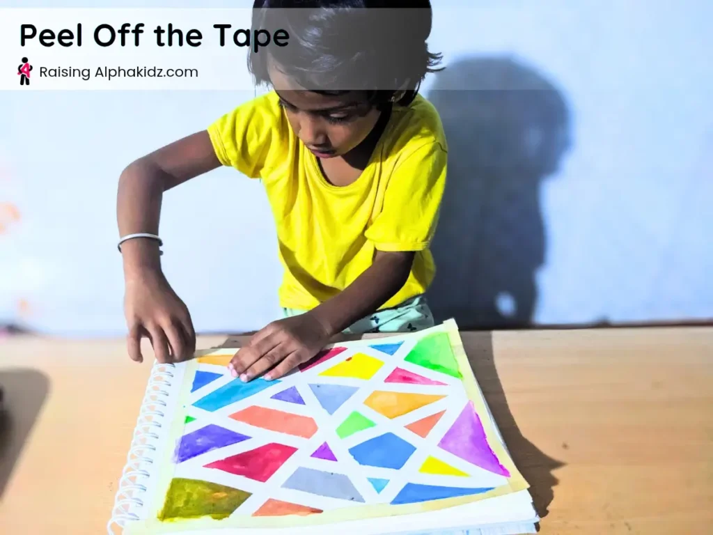 removing masking tape to reveal tape resist art pattern