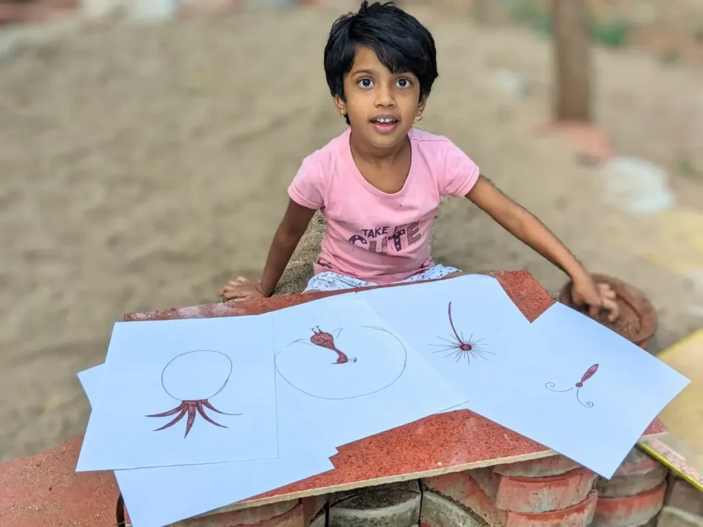 kid sitting on outdoor space with mud painting template papers