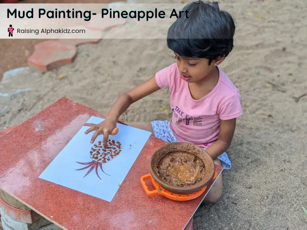 kid making mud dots inside pineapple outline for mud painting
