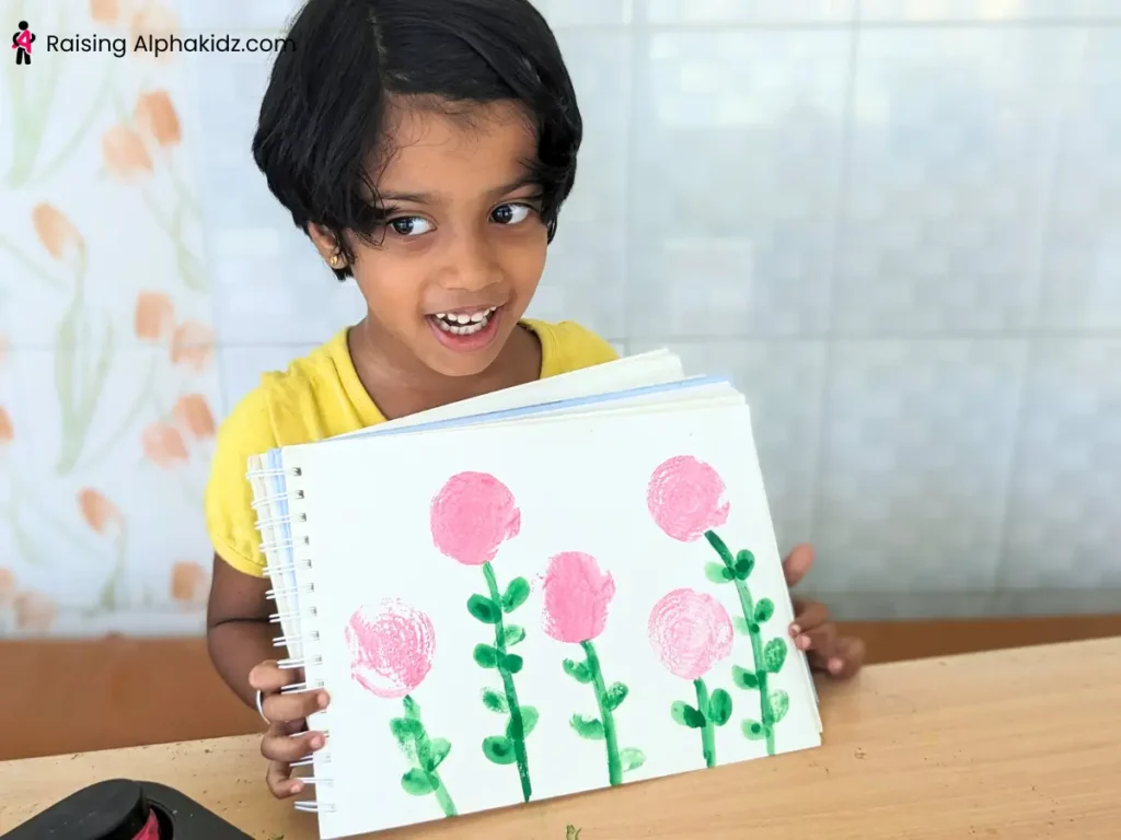 child showing finished onion stamp art flowers created with onion dabbing painting activity