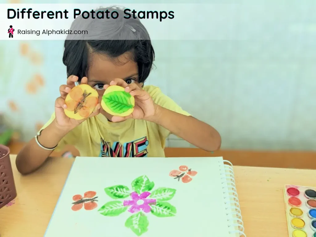 kid showing butterfly and leaf potato stamp art with paint colors