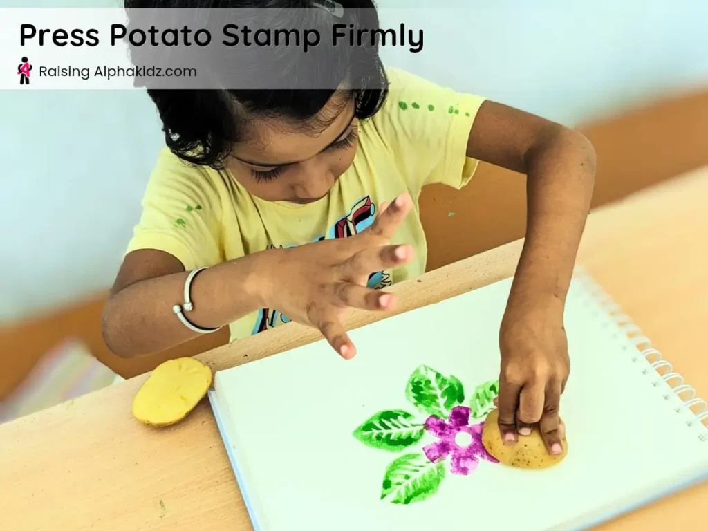 kid pressing leaf potato stamp art firmly on canvas