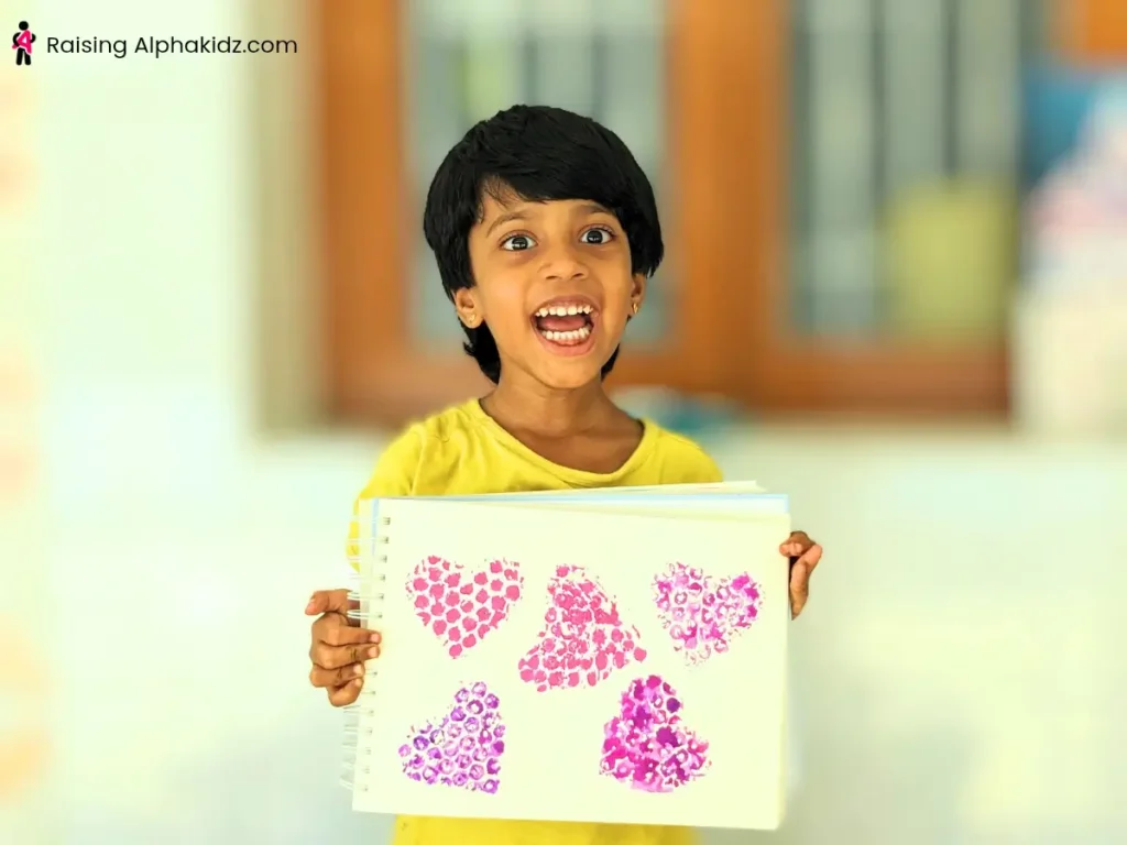 A kid happily showing the heart Prints made from bubble wrap stamps