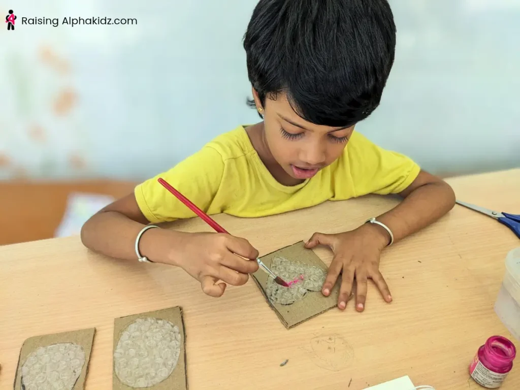 A kid adding paints to bubble wrap stamp