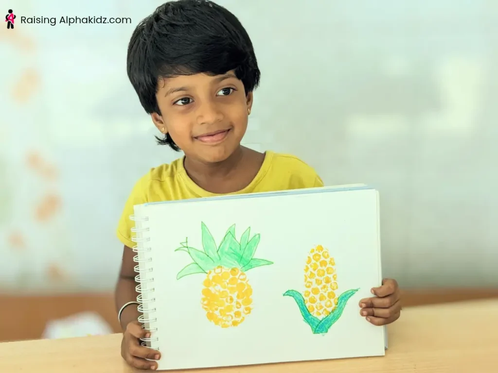 A kid showing pineapple and corn prints made out of bubble wrap stamps