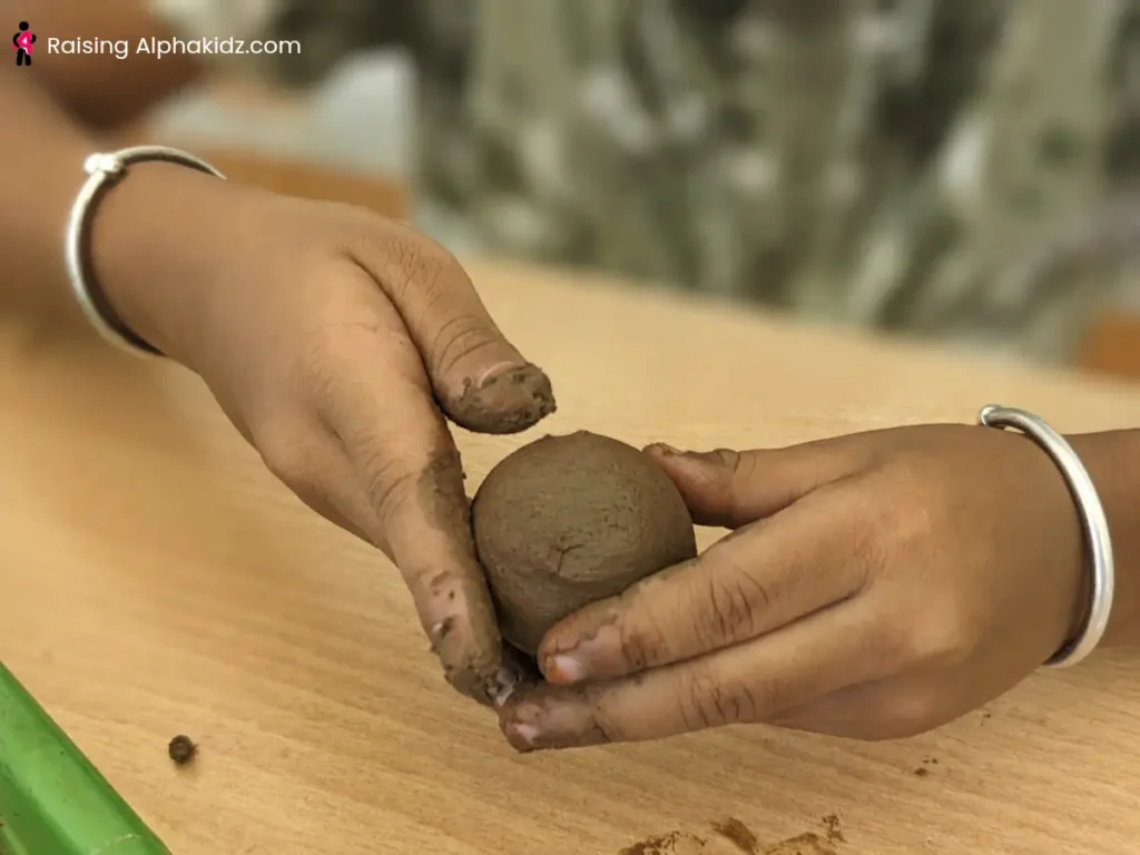 Child rolling clay into a smooth ball