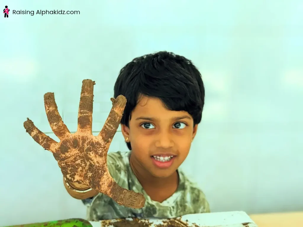 Child shaping wet clay by hand 