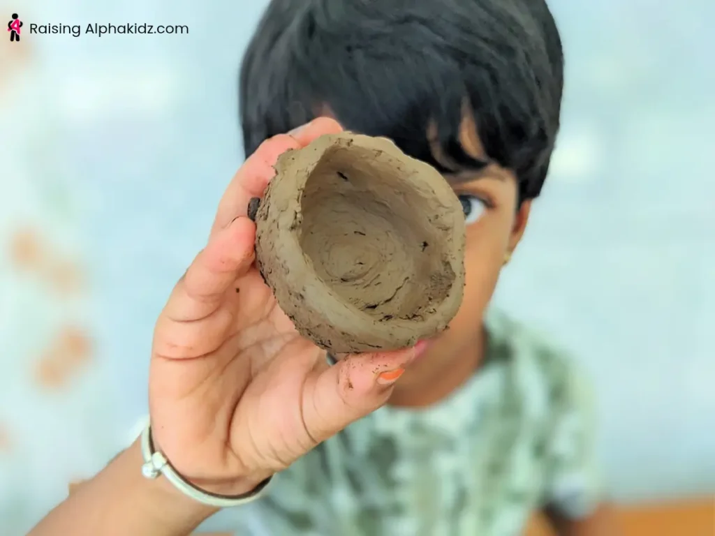 Smoothing the rim and surface of a handmade clay pinch pot