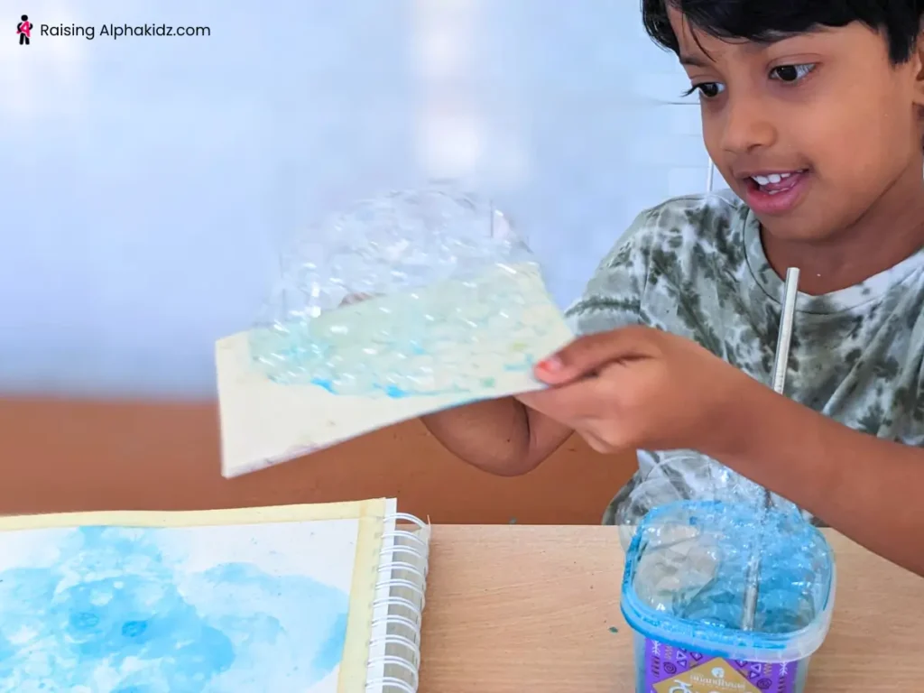 Kid transferring the bubbles to the canvas to make bubble art