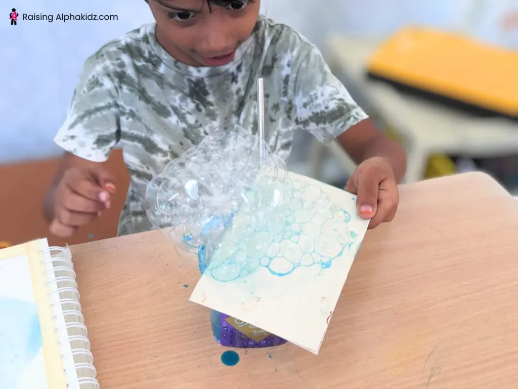 Kid using card to take the bubbles out of bowl